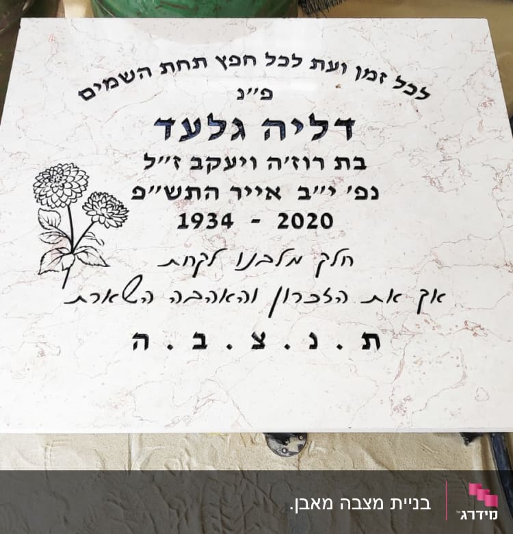 מצבה עם כיתוב בעברית ופרח חקוק